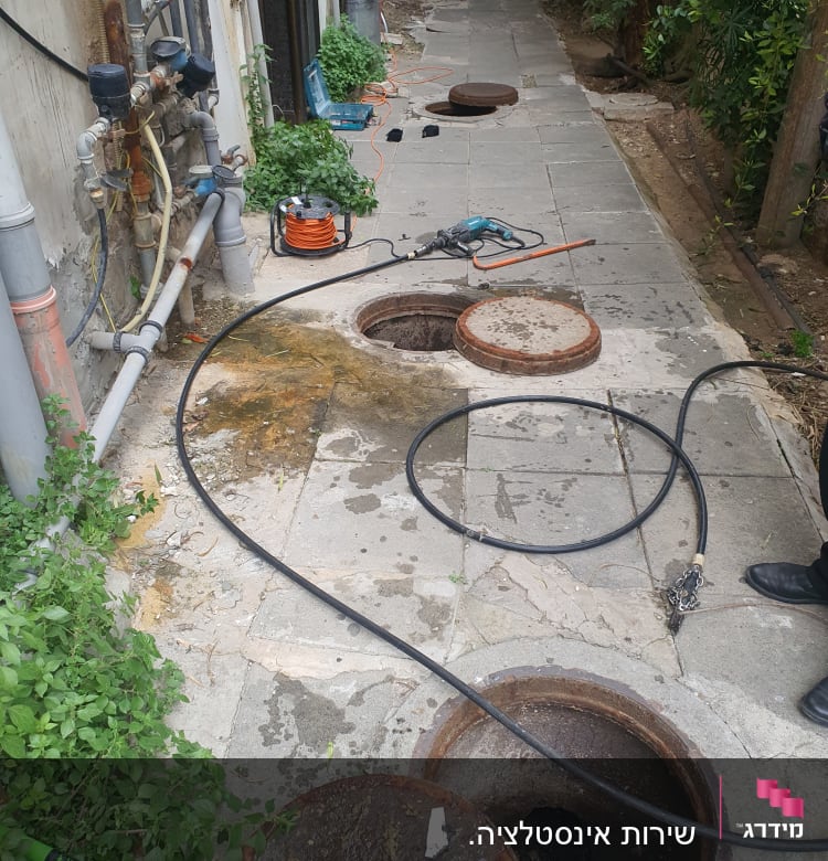 צינורות וכלי עבודה ליד פתח ביוב פתוח